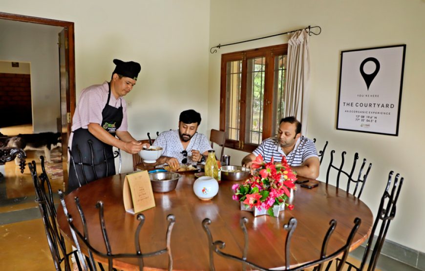 Two persons eating and one person is serving the food in the farm house stay in Bangalore